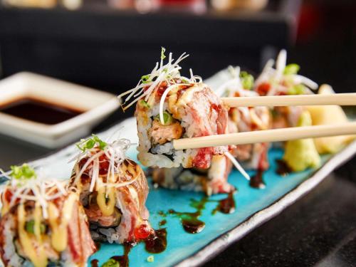 a group of sushi on a blue plate with chopsticks at Grand Mercure Bangkok Atrium in Bangkok