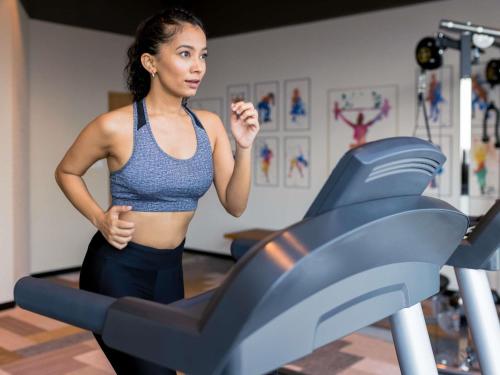 a woman running on a treadmill in a gym at ibis Thane - An Accor Brand in Thane