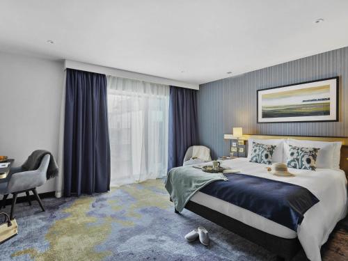 a hotel room with a large bed and a desk at Mercure Paignton Hotel in Paignton