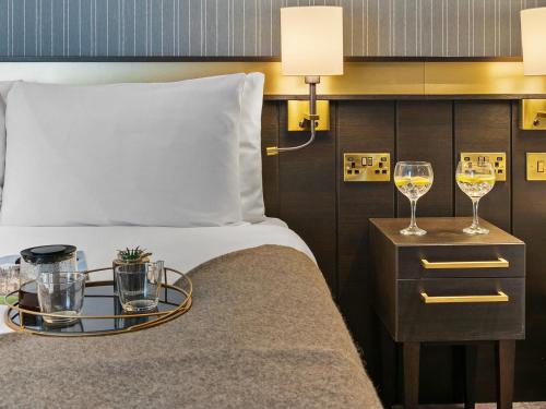 a hotel room with a bed with two glasses of wine at Mercure Paignton Hotel in Paignton
