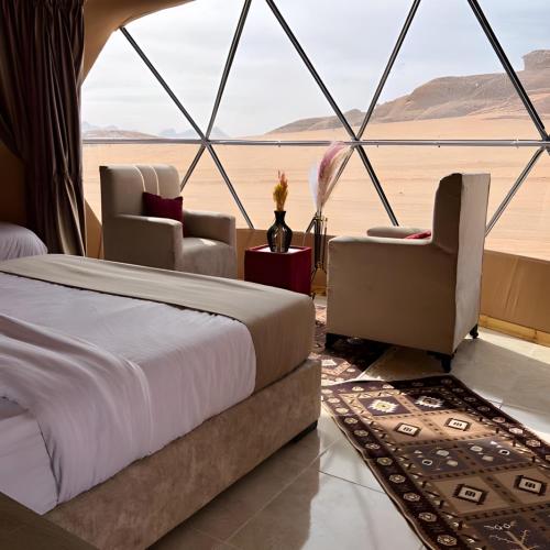 a bedroom with a bed and chairs and a view of the desert at Volta Desert Camp in Wadi Rum