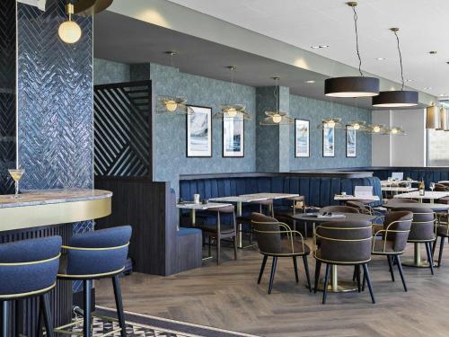 a restaurant with tables and chairs and a bar at Mercure Paignton Hotel in Paignton