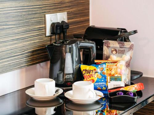 a table with a coffee maker and cups on it at Mercure Singapore Tyrwhitt in Singapore