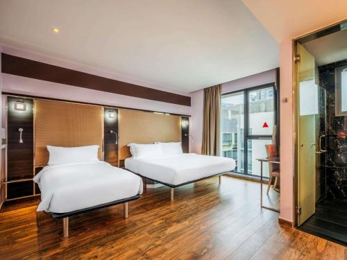 a bedroom with two beds and a large window at Mercure Singapore Tyrwhitt in Singapore