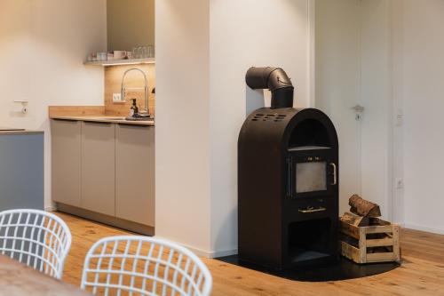 a wood stove in a kitchen with two chairs at HØV - Boutique-Apartments im Allgäu - Rückzug & Design in Altusried