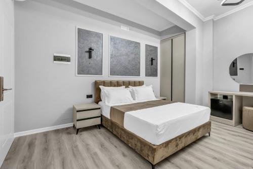 a white bedroom with a bed and a tv at Villa Soni in Berat