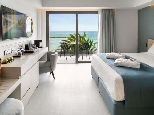 a bedroom with a bed and a view of the ocean at Mercure Larnaca Beach Resort in Larnaka