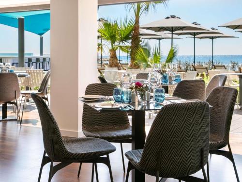 a dining room with a table and chairs and the ocean at Mercure Larnaca Beach Resort in Larnaka