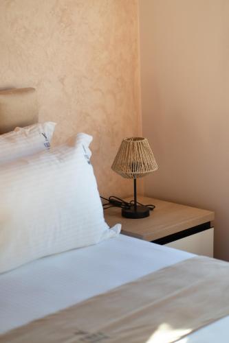 a bed with white sheets and a lamp on a night stand at Villa Soni in Berat