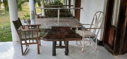 an old wooden table and chairs on a porch at Baby Bird Luxury Studio in Ukunda
