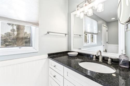 ein weißes Badezimmer mit Waschbecken und Spiegel in der Unterkunft Lagoon Villa 19 - Lagoon Lifestyle! Center of Wild Dunes! in Isle of Palms