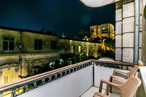 balkon z dwoma krzesłami i widokiem na budynek w obiekcie ISKCON Apartment w mieście Baku