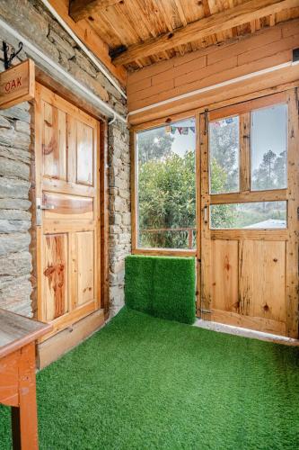 a room with green flooring and a wooden door at Stonewood Homestay in Jageshwar