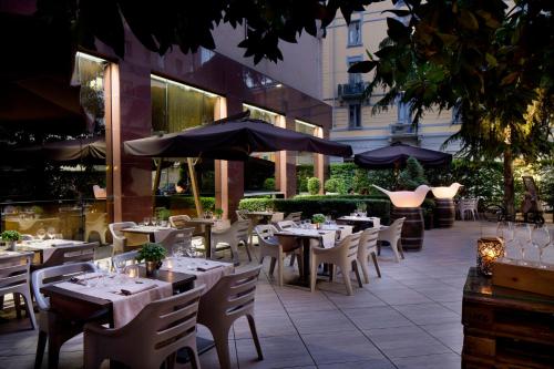 an outdoor restaurant with tables and chairs and umbrellas at Starhotels Ritz in Milan