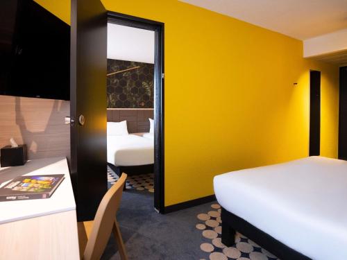 a room with two beds and a yellow wall at ibis Styles Strasbourg Nord Palais des Congrès in Schiltigheim