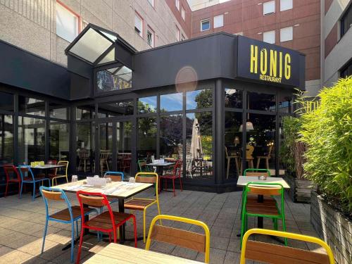 a restaurant with tables and chairs in front of a building at ibis Styles Strasbourg Nord Palais des Congrès in Schiltigheim