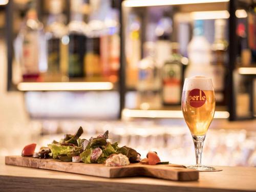 a glass of beer next to a plate of food at ibis Styles Strasbourg Nord Palais des Congrès in Schiltigheim
