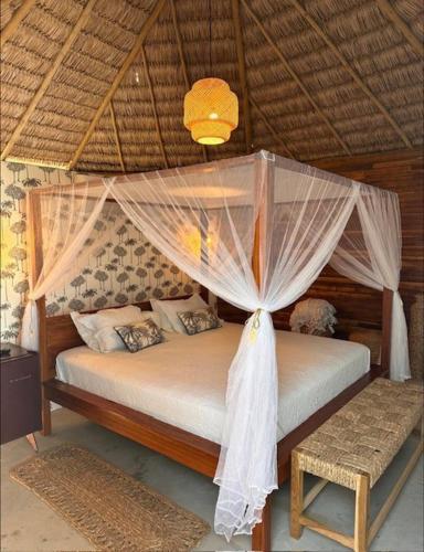una camera da letto con un letto a baldacchino e una panca di Villa kite a Itarema