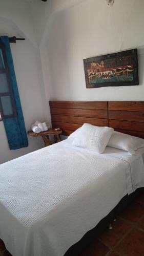 a bedroom with a white bed with a wooden headboard at Terraza De San Antonio in Cali