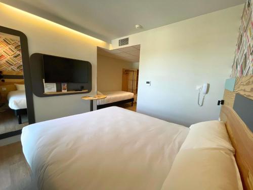 a hotel room with a white bed and a television at greet hotel Castets Coeur des Landes in Castets