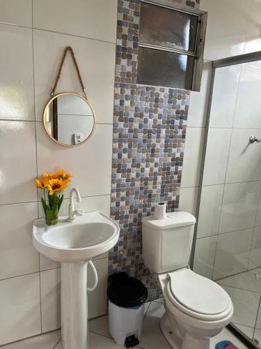 a bathroom with a toilet and a sink and a mirror at Residência Oliveira in Prado