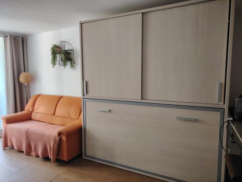an orange chair sitting next to a large closet at Apartamento centrico en Calella in Calella