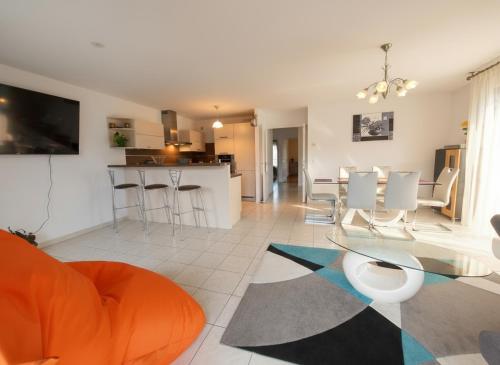 a living room with a glass table and a kitchen at Au cœur de St Jorioz, spacieux appartement avec terrasse et vue montagne. in Saint-Jorioz