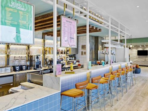 a restaurant with a bar with orange stools at ibis Styles Paignton in Paignton
