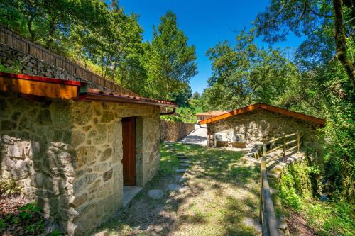 an outside view of two stone buildings with trees at Moinhos do Coto in Vila Verde