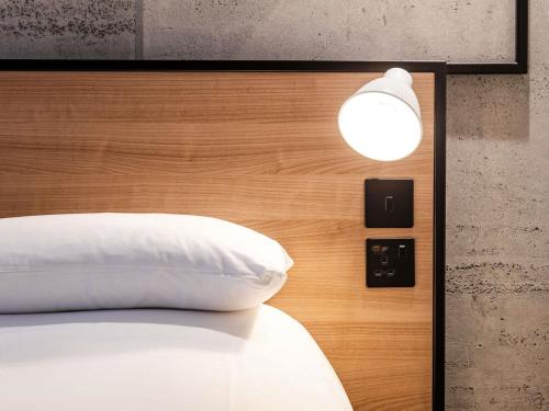 a bedroom with a bed with a white pillow and a light at ibis Coleraine Riverside in Coleraine
