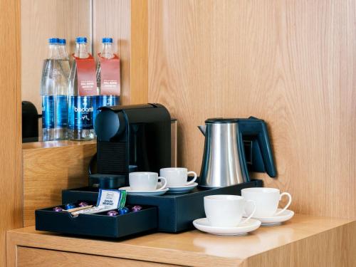 a coffee maker with cups and cups on a shelf at Movenpick Winter Park Baku in Baku