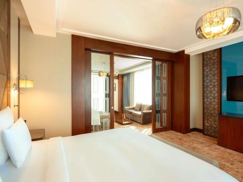 a bedroom with a large bed and a living room at Movenpick Winter Park Baku in Baku