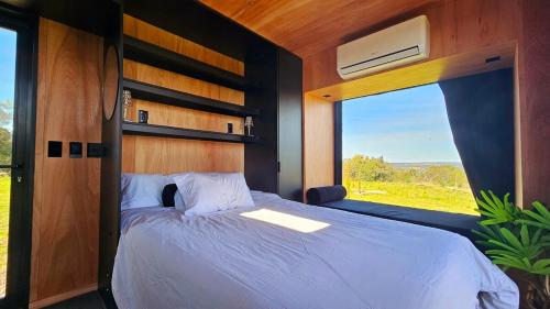 una camera da letto con un letto grande e una grande finestra di NEW! Casa de campo con diseño - Casa Armonia Uruguay a Aiguá
