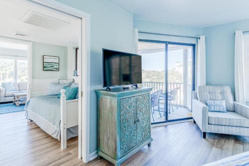 a bedroom with a bed and a tv and a balcony at Port O' Call G304 - Modern Oceanview! Atlantic Escape! in Isle of Palms