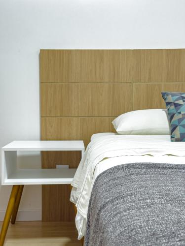 a bedroom with a bed with a wooden headboard and a table at Apartamento Melhor Localizado em Pomerode in Pomerode