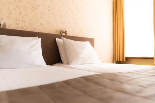 a bed with white sheets and pillows in a bedroom at Hotel Restaurant 't Heerenlogement in Harlingen