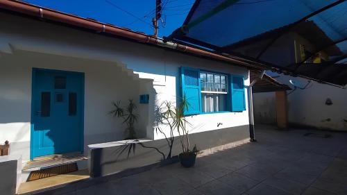 une maison blanche avec des fenêtres bleues et une plante en pot dans l'établissement Refúgio Caiçara, à Parati