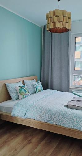 a bedroom with a large bed with blue walls at Gold Key komfortowy apartament z balkonem, klimatyzacja i parkingiem in Pruszków