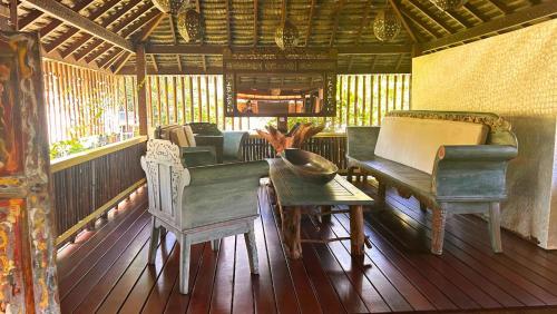 a living room with a piano and chairs on a porch at TAHITI - Fare Matovai in Aua