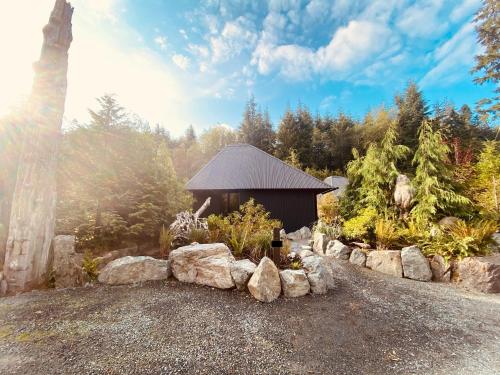 a building with rocks in front of a forest at Fern's Edge in Port Renfrew