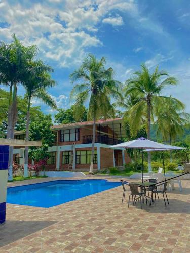 a house with a pool and a table with an umbrella at Casa campestre el samán in Utica