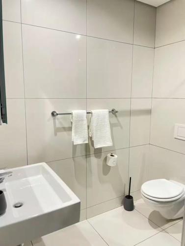 a white bathroom with a sink and a toilet at ProAvia Apartments and Hotel in Windhoek