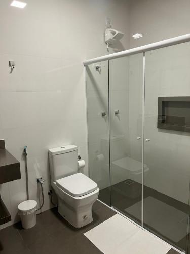 ein Badezimmer mit Toilette und Glasdusche in der Unterkunft Keko Hotel in Guapiaçu