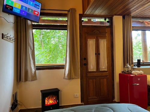 une pièce avec une cheminée, une télévision et une porte dans l'établissement Chalé Santo Antônio do Pinhal, à Santo Antônio do Pinhal