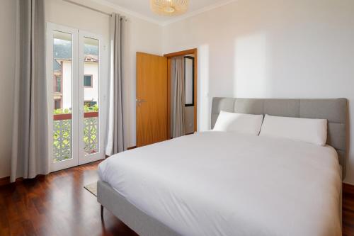 una camera da letto con un grande letto bianco e una finestra di Casa Jardim Celeste a Seixal