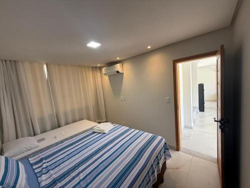 a bedroom with a bed with a blue and white striped sheet at Linda casa a 150mts da Praia in Camaçari