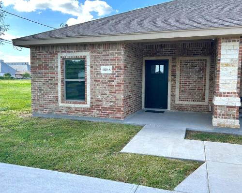 a brick house with a blue door and a sidewalk at Quiet 2BR Retreat , Fenced yard , Modern Duplex in Harlingen