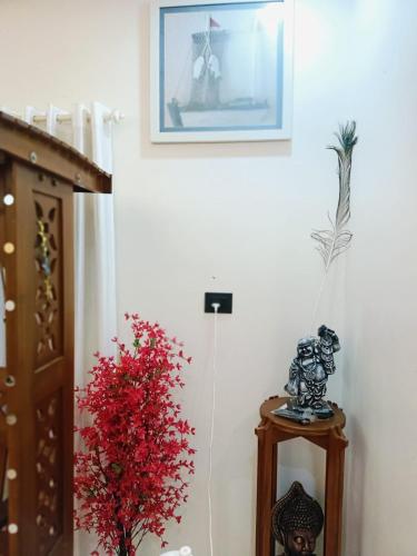 a vase of red flowers on a table next to a wall at Pepper Jazz Varkala in Varkala