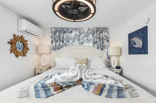 two swans towels on a bed in a bedroom at Boating Enthusiasts, Walk to the Beach, Heated Pool - The Corner cottage - Roelens in Fort Myers Beach