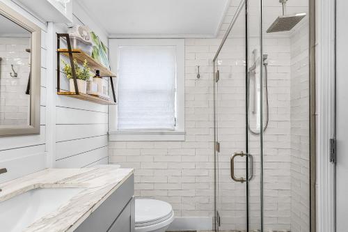 a white bathroom with a shower and a toilet at Boating Enthusiasts, Walk to the Beach, Heated Pool - The Corner cottage - Roelens in Fort Myers Beach